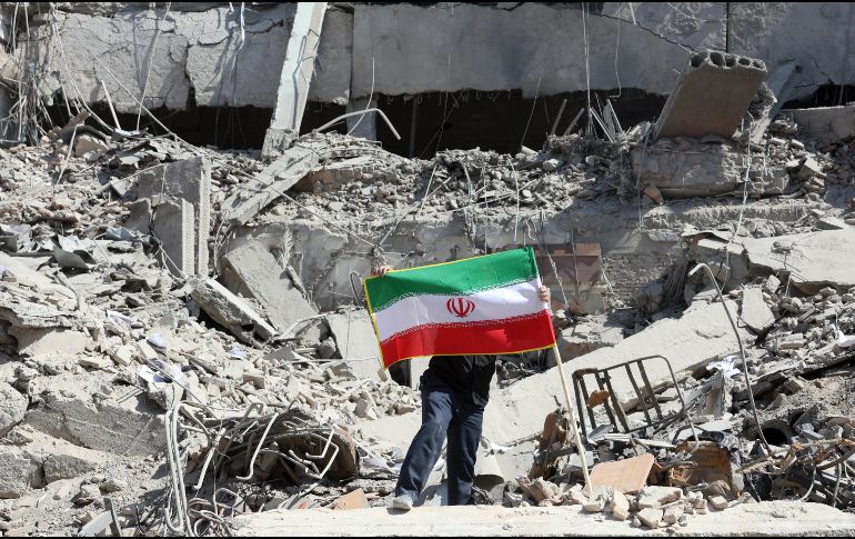 Un iraní coloca la bandera nacional de Irán entre las ruinas de una comisaría de policía dañada en el centro de Teherán, Irán, este miércoles. EFE/ A. Taherkenareh