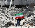 Un iraní coloca la bandera nacional de Irán entre las ruinas de una comisaría de policía dañada en el centro de Teherán, Irán, este miércoles. EFE/ A. Taherkenareh