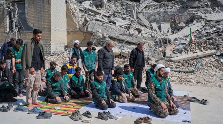 Un grupo de voluntarios basijis -milicia islámica- reza este miércoles, al lado de un edificio destruido en los bombardeos israelíes-estadounidenses contra Irán en la calle en la calle Kargar, cerca de la plaza Engelab en Teherán. EFE/ J. León