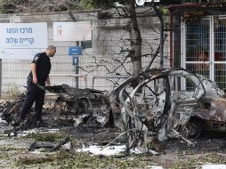 Un policía israelí inspecciona coches calcinados tras el impacto de fragmentos de un misil balístico iraní interceptado en Tel Aviv, Israel, el 15 de marzo de 2026. EFE/A. SULTAN