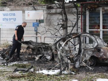 Un policía israelí inspecciona coches calcinados tras el impacto de fragmentos de un misil balístico iraní interceptado en Tel Aviv, Israel, el 15 de marzo de 2026. EFE/A. SULTAN